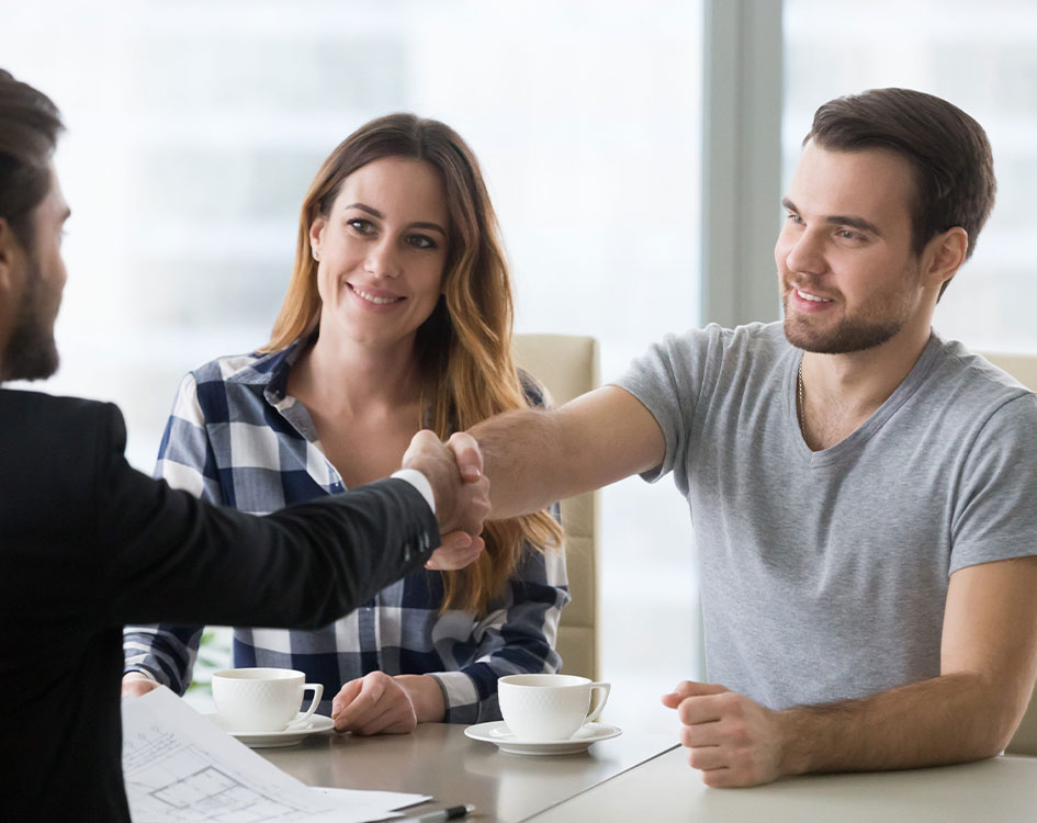 Jóvenes estrechando la mano con un asesor comercial.